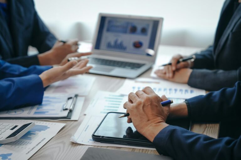 Professional business team meeting in formal suits, working at desks with financial papers